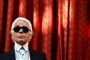 Karl Lagerfeld som man kender ham. Med store solbriller, sort jakkesæt og det hvide hår trukket tilbage i en lille hestehale.