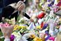 En pige placerer her blomster for at mindes ofrene fra fredagens angreb ved to moskéer i Christchurch i New Zealand.
