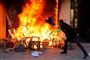 En af de mange protesterende i Paris nær en butik i flammer under de voldsomme protester i den franske hovedstad lørdag.