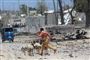 En mand løber forbi den bil, der blev brugt i en selvmordsaktion mod en regeringsbygning i Mogadishu lørdag.