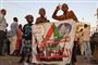 "Revolution er folkets valg", står der på et banner, som tre sudanske børn holder frem under torsdagens demonstration uden for militærets hovedkvarter i hovedstaden Khartoum.