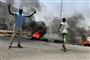 Demonstrant i Khartoum viser v-tegnet for sejr, mens bildæk er sat i brand nær forsvarsministeriet. Kort forinden har soldater stormet demonstranternes protestlejr tæt på ministeriet og dræbt mindst 30ifølge læger.