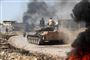 En tank tilhørende den tyrkiskstøttede oprørssammenslutning Den Nationale Befrielsesbevægelse (NLF) ses her køre ind i den syriske provins Hama torsdag. Brændende dæk skaber et røgslør mod luftangreb fra regeringsstyrkerne.