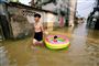 En mand trækker sin datter, som sidder i et oppusteligt badebassin, i en oversvømmet landsby nær Hanoi efter en tropisk storm i juli 2018. (Arkivfoto)