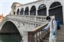 En kommunalt ansat sprøjter desinficerende væske på Rialto-broen i Venedig onsdag som led i indsatsen for at begrænse smittespredningen.