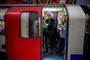 Passager i Londons undergrundsbane med maske for at beskytte sig mod coronavirus. Nu lukker en lang række stationer, og busdriften i byen   begrænses.