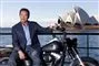 Arnold Schwarzenegger på motorcykel med Sydney Opera Hus i baggrunden.