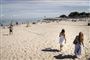 Solbeskinnet strand med sommeklædte mennesker på