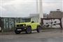 En grøn Suzuki foran grafittimur