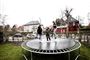 tre børn hopper på en trampolin i haven 
