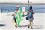 Badegæster går på stranden med et badedyr formet som en krokodille