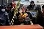 Dame med maske og favnen fuld af blomster til en begravelse