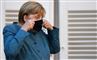 Angela Merkel i blå kjole med et sort mundbind.