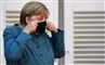 Angela Merkel i blå kjole med et sort mundbind.