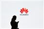 En silhouet af en kvinde med en mobiltelefon foran et stort Huawei-reklame