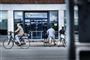 Et jobcenter med en cylende mand i forgrunden og to mænd som trækker deres cykler