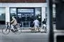 Et jobcenter med en cylende mand i forgrunden og to mænd som trækker deres cykler