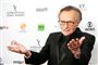 En ældre og svageligt udseende Larry King slår ud med sine arme