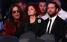 Ozzy Osbourne sidder med solbriller på ved siden af sin kone Sharon, som ser sur ud. Parrets søn Jack Osbourne er også med på billedet. Han sidder ved siden af sin mor med et sort jakkesæt og en hvid skjorte på.