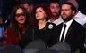 Ozzy Osbourne sidder med solbriller på ved siden af sin kone Sharon, som ser sur ud. Parrets søn Jack Osbourne er også med på billedet. Han sidder ved siden af sin mor med et sort jakkesæt og en hvid skjorte på.