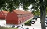 Forsvarets Efterretningstjeneste holder til på Kastellet i København som her er afbilledet. Det er nogle gamle rødmalede bygninger. Der ses også en parkeringsplads på billedet.
