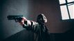Mand i et værelse peger med en pistol
