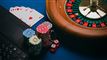 En roulette, jetoner og nogle spillekort på et bord