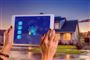 Person holder ipad op foran hus med lys i
