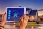 Person holder ipad op foran hus med lys i