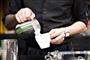 mand hælder mælk fra kande i kaffekop 