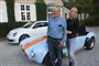 Janni og Karsten foran et stort hus med VW og Cobra-biler bag dem
