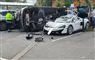 Bil ligger på siden ved siden af smadret McLaren