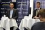 Billede af Erik Brøgger ved onsdagens pressemøde. Han står ved et højt cafébord med en hviddug. Ved et andet bord ved siden af ses Søren Brostrøm