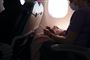 Billede inde fra et fly man ser en række personer i modlys fra flyets genkendelige runde vindue