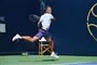 En tennisspiller giver en baghånd på banen