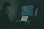 Mand sidder i mørke foran computerskærm