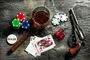 Jetoner, kort, terninger, en cigar, en whisky og en Colt revolver på et bord
