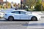 En hvid Tesla med skrammer og buler langs siden