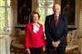 Portræt af dronning Sonja og kong Harald. Sonja er i en postkasserød blazer med en hvid skjorte under. Kongen er iført jakkesæt. 