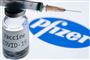 En sprøjte ovenpå en lille beholder med væske, hvor der står Covid-19 Vaccine