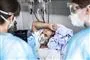 person med mundbind ligger i hospitalsseng
