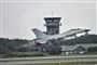 Et F16-fly letter med et kontroltårn i baggrunden