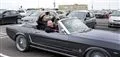 LOC griner på passagersædet af en åben Ford Mustang