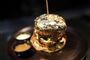 Guldbelagt burger på tallerken med dip ved siden af.