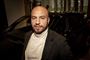 Nærbillede af Dar Salim iført hvid rullekravestrik og en brun blazer.