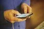 person står med mobiltelefon i hånden