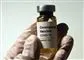 hånd med handske holder glas med vaccine