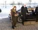Kong harald og hans kone Sonja med mundben på efter de er steget ud af en bil. Kongen bruger stok på billedet. 