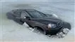 En sort Volvo næsten dækket af vand og omgivet af is. 