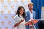 Meghan og Harry smiler og taler i en mikrofon